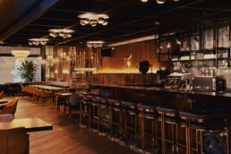 Warm and stylish interior of a modern steakhouse restaurant with golden lighting, elegant bar seating, and cozy dining tables, promotional photography by Vidora Studio.